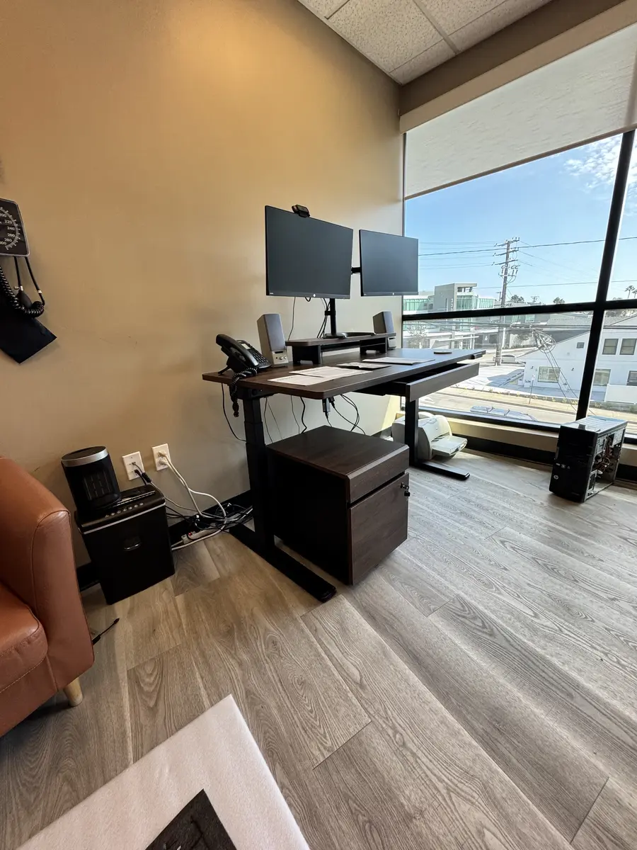 Sit-stand desk with dual monitor arm assembled in a Newport Beach office, August 2026